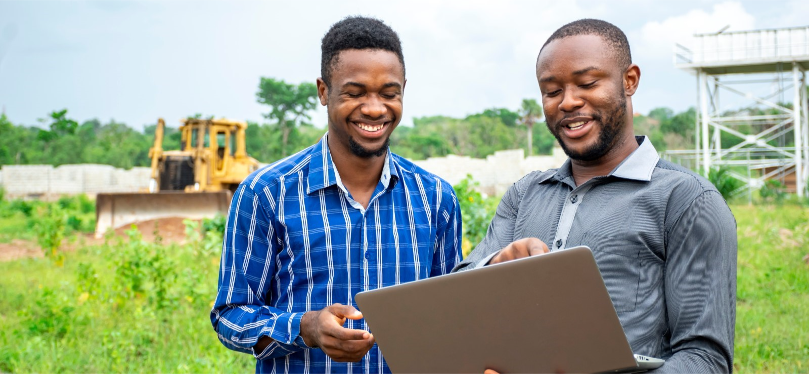 Two men talking while looking at a laptop