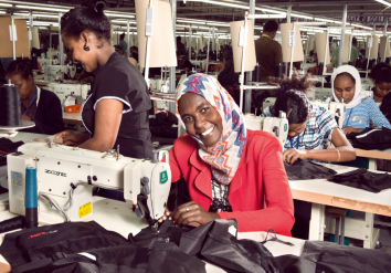 A similing woman working with a sewing machine